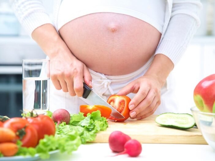 Mulher grávida preparando alimentos saudáveis