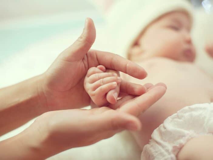 Mãe segura nas mãos do seu bebê