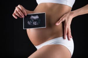 Mulher grávida segura imagem do exame de ultrassom de seu bebê